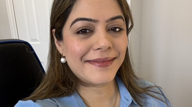Selfie of a girl named Vasudha Sharma wearing a blue collared top, smiling into the camera.